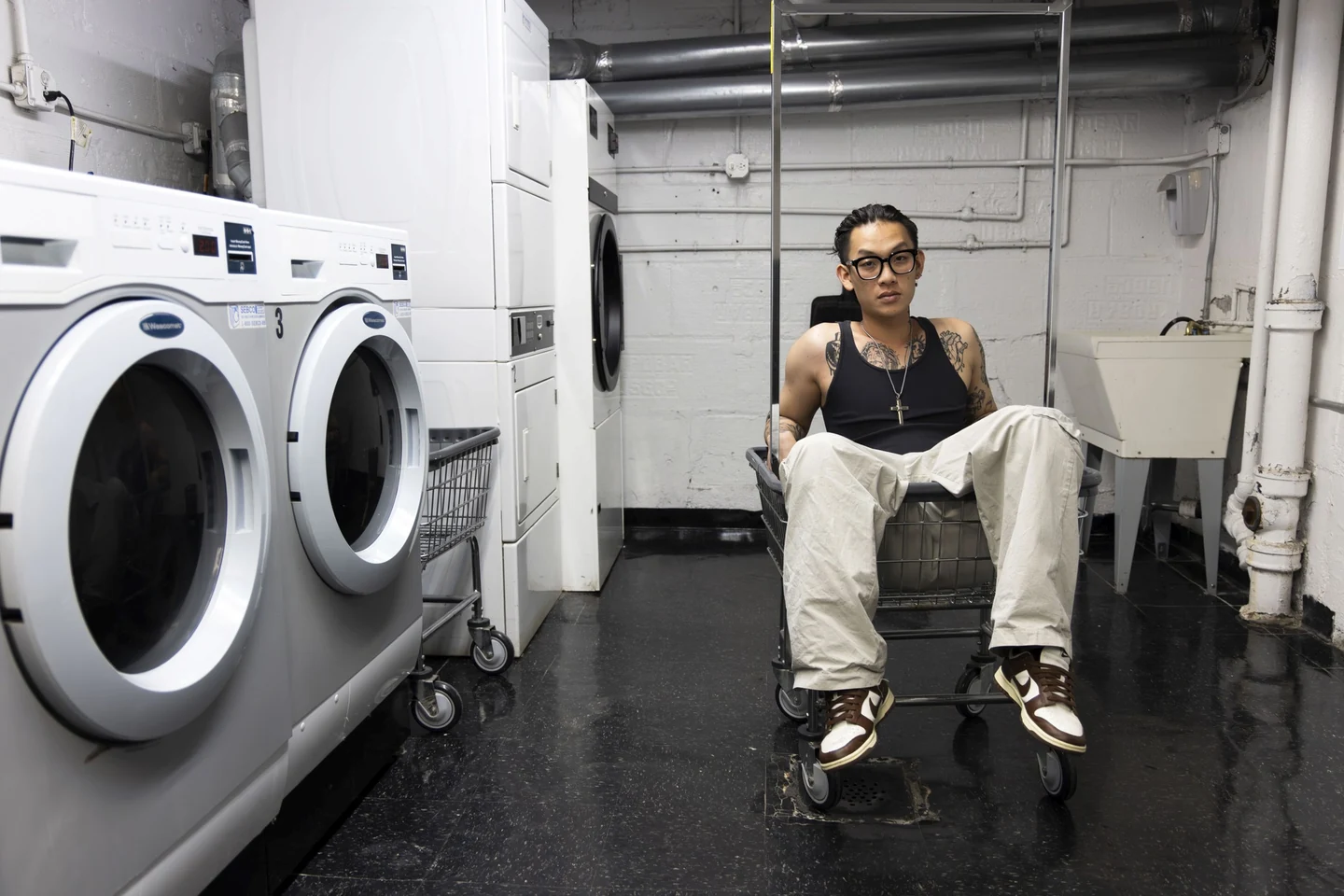 Win Tang seated between machines in a laundry room
