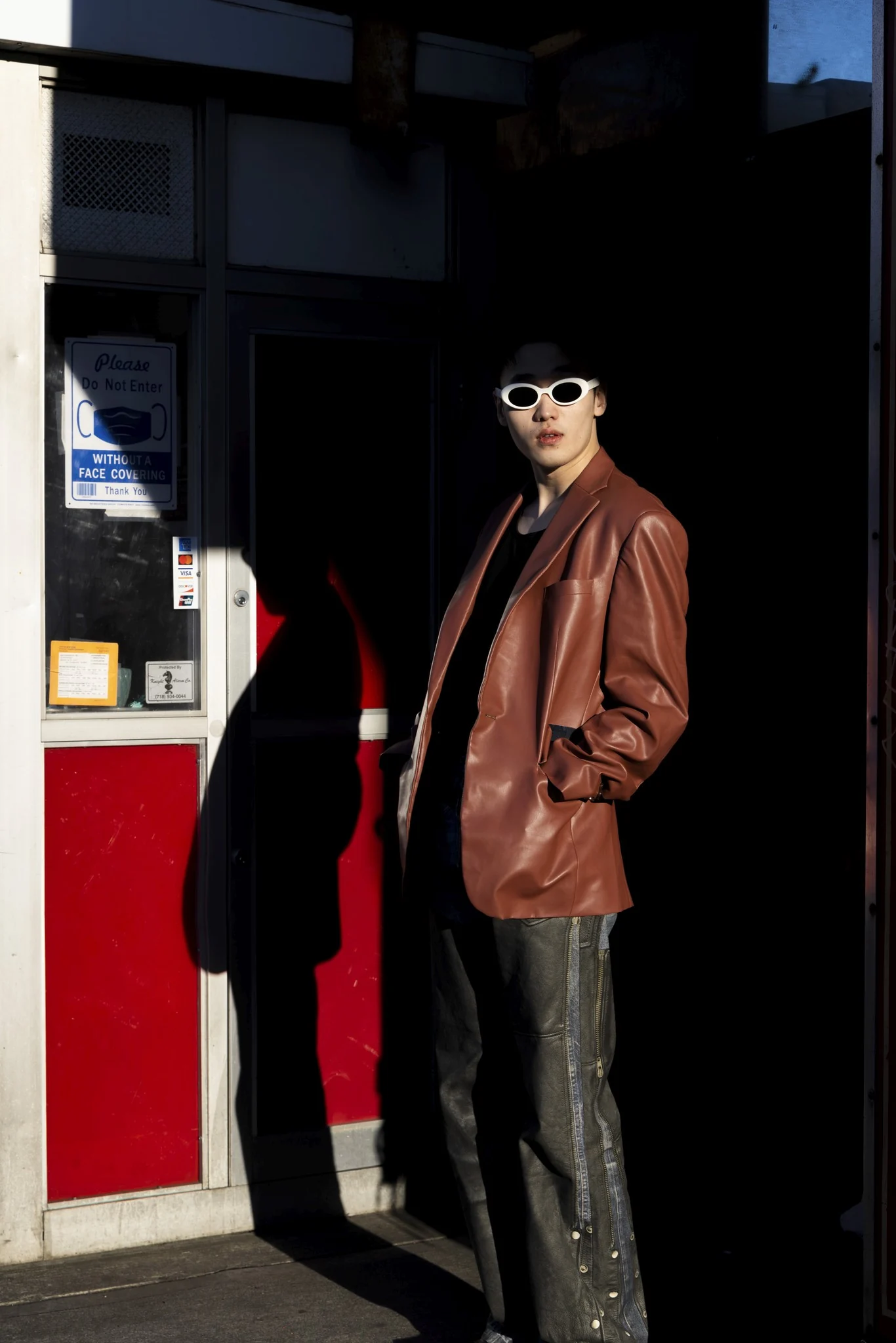 Quintus in a brown jacket outside a dark storefront