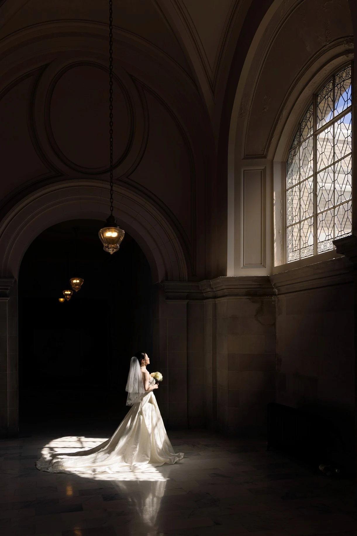 Bride beneath a vaulted ceiling in a pool of window light